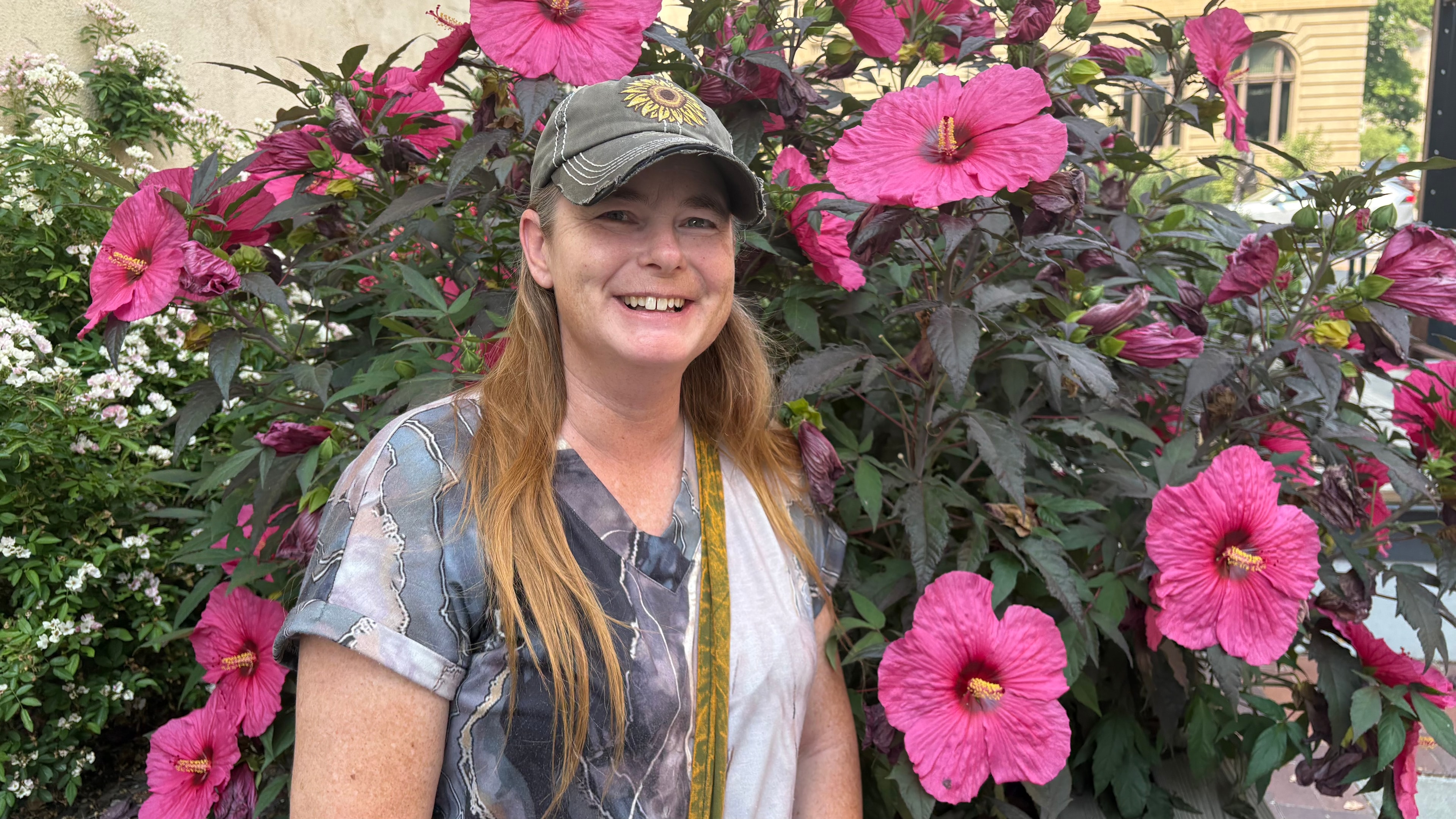 Susan standing among vibrant pink hibiscus flowers